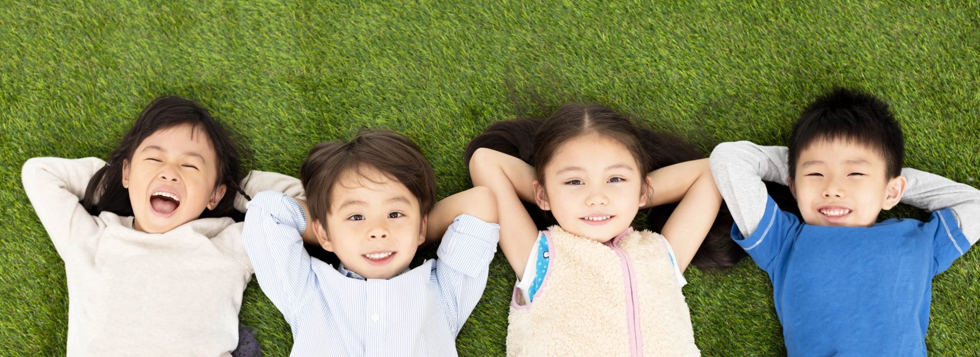 Young children lying on the ground and smiling up at the camera